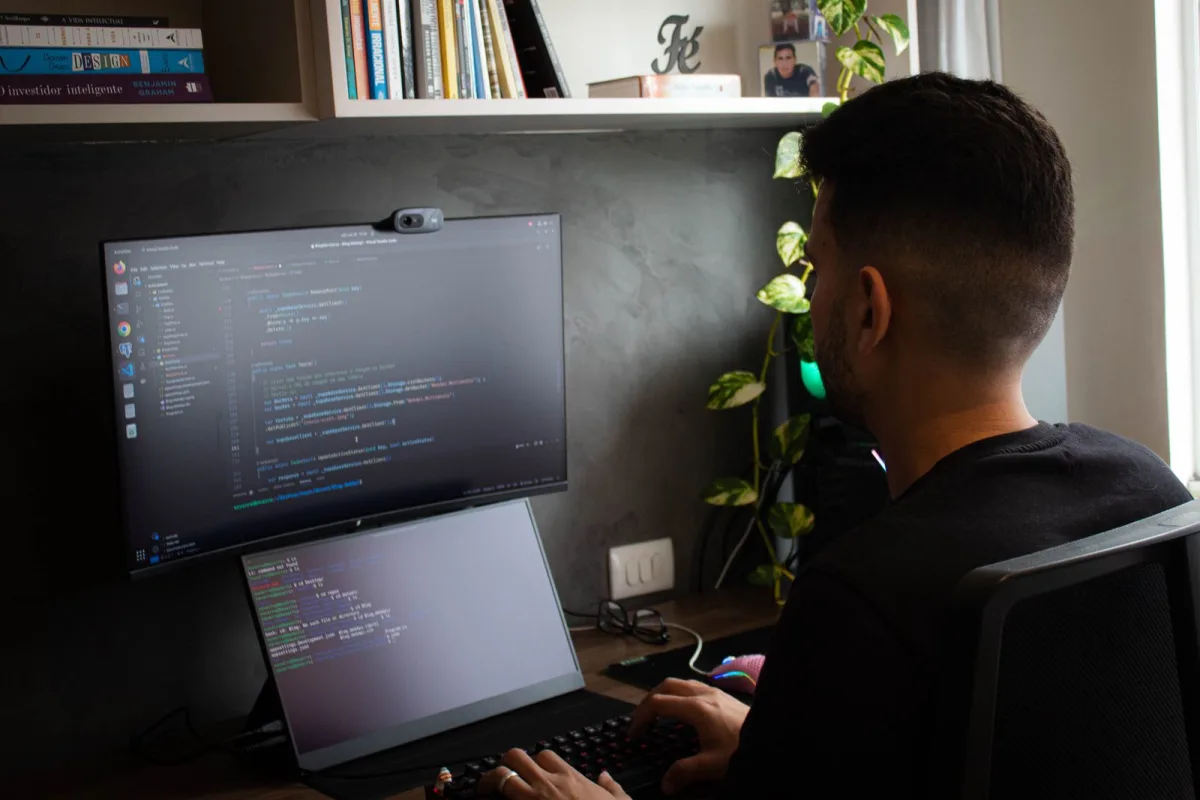 Developer's desk at night with code on monitors and a security warning alert on screen