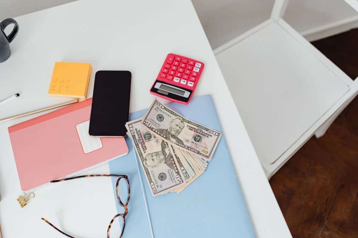 Overhead view of a desk with a calculator, paper bills and glasses, representing payroll deductions and tax planning