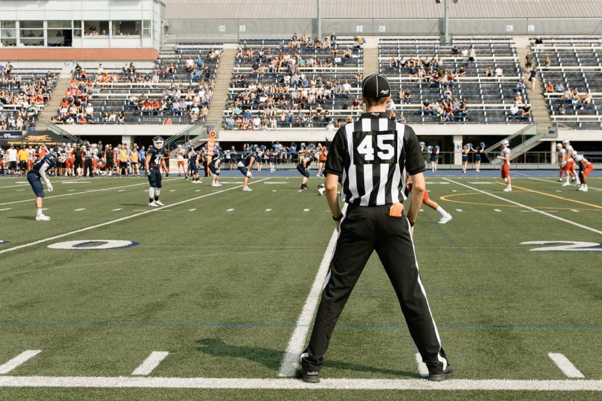 A Canadian football game in progress under stadium lights in a packed stadium