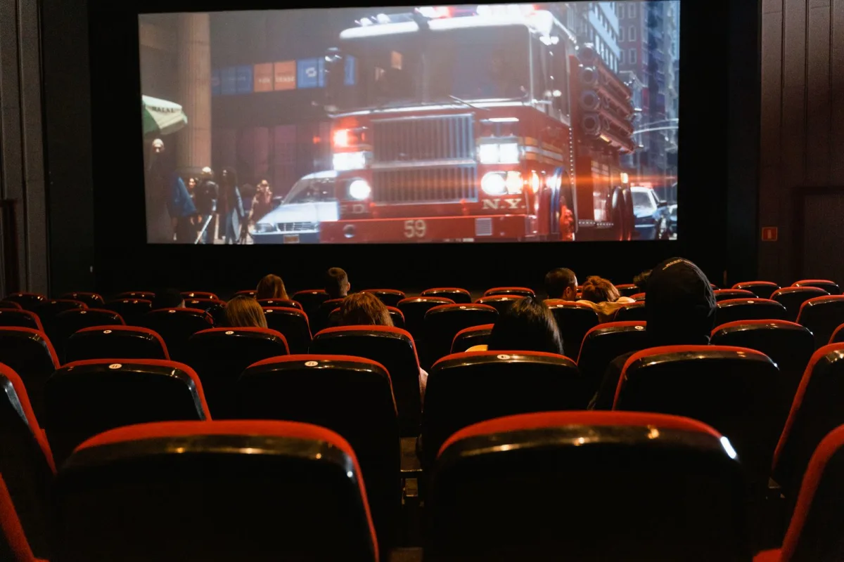 People seated in a cinema watching a movie on a large screen