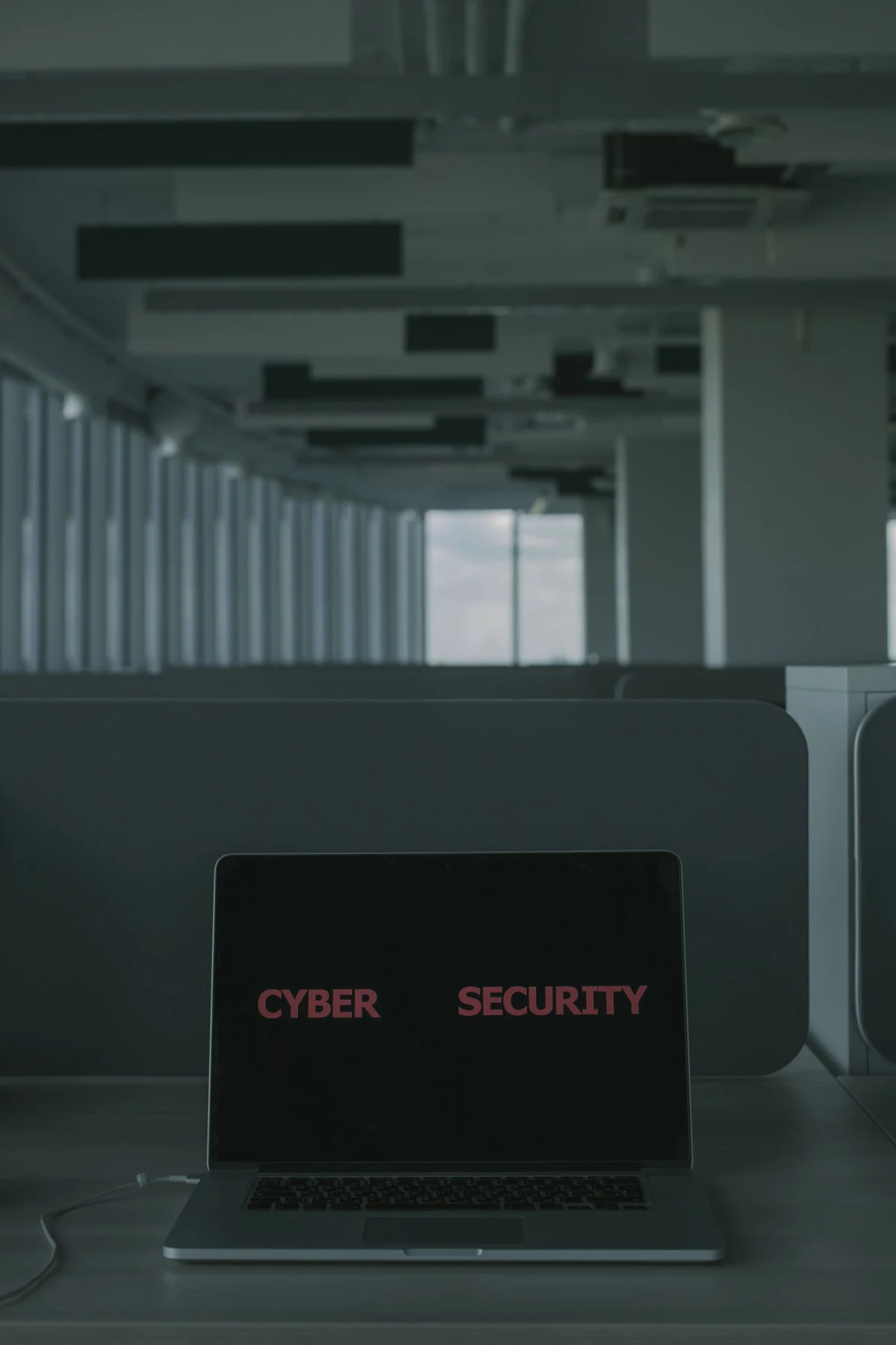 A laptop displaying cybersecurity graphics with a digital padlock overlay on a desk