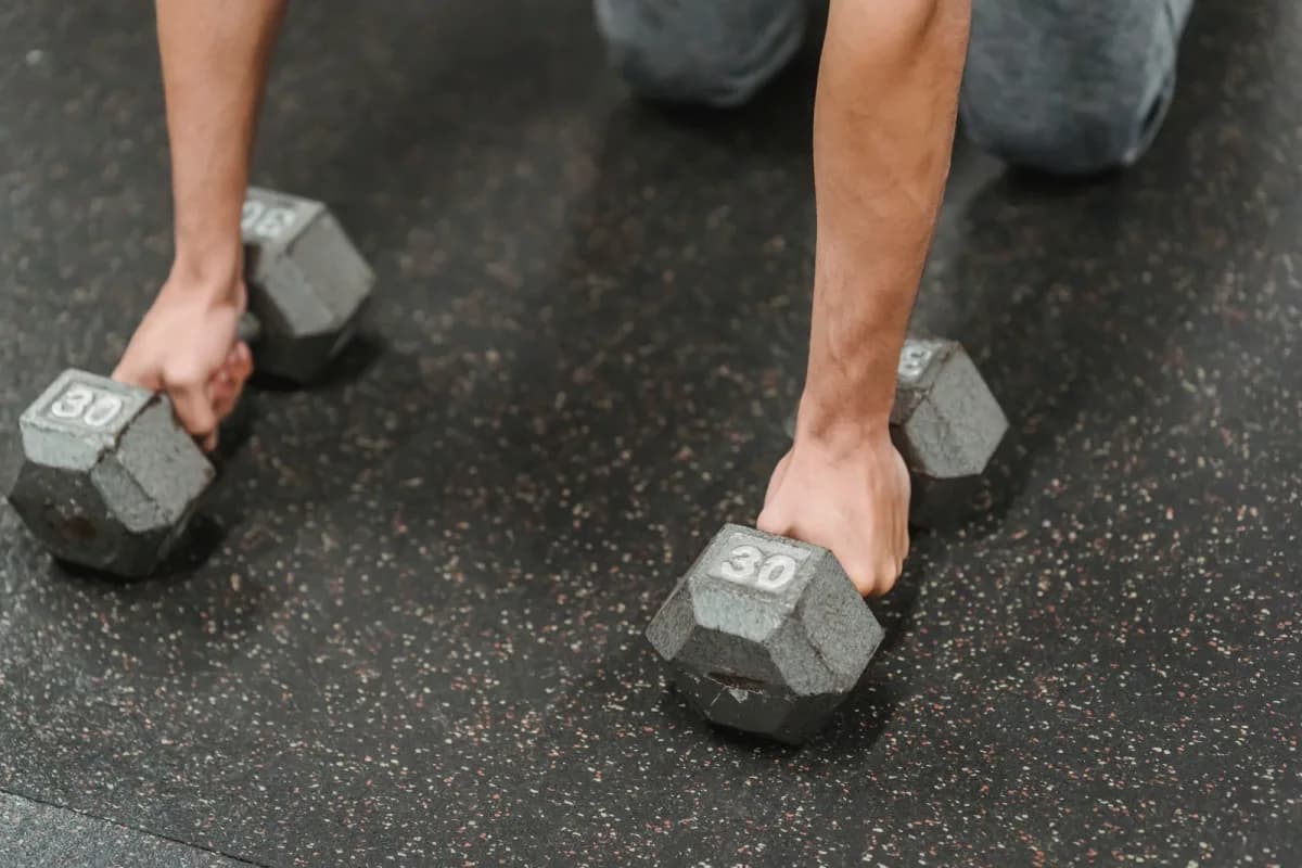 A man doing a strength training exercise with heavy dumbbells in a gym