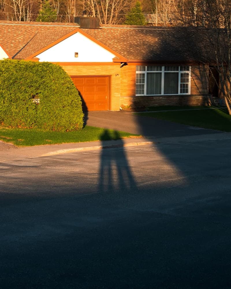 Calculator and mortgage paperwork beside an image of Canadian suburban houses at sunset