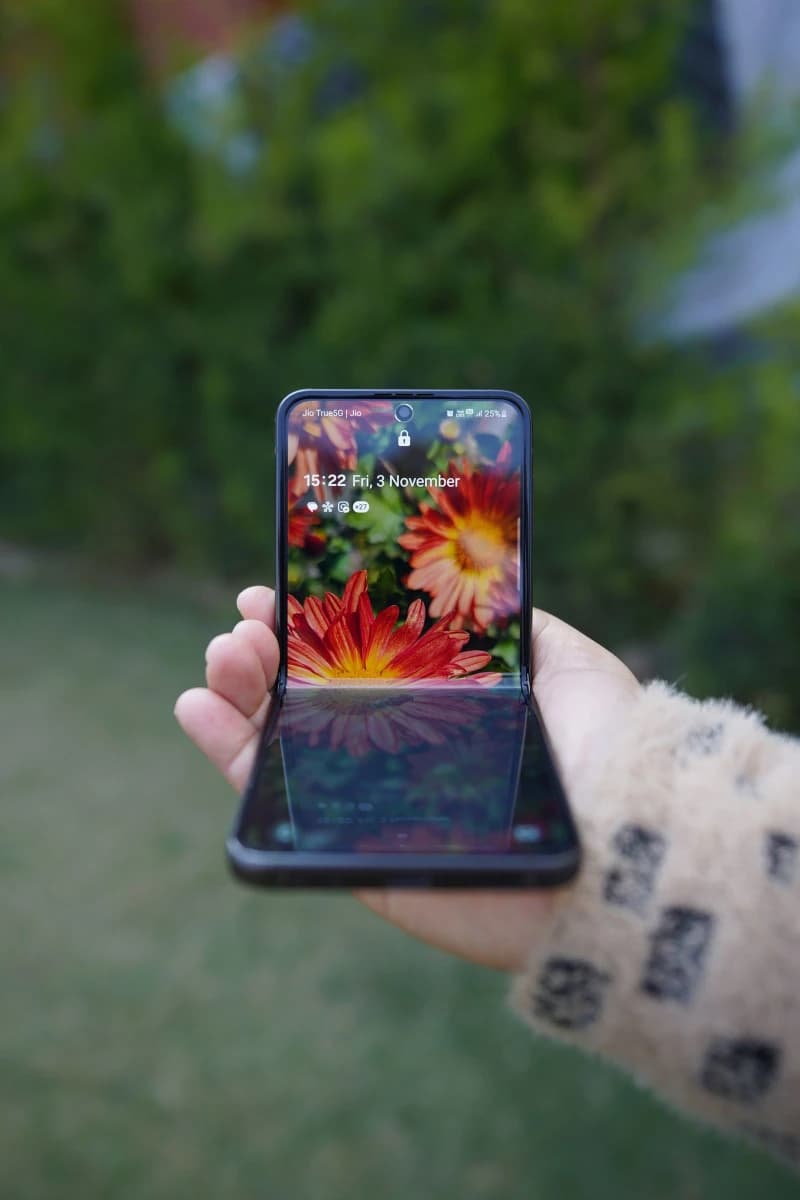 A foldable smartphone photographed half-open, displaying a large inner screen against a dark background