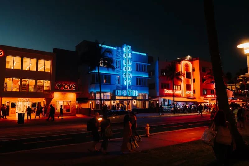 Neon-lit Vice City style street at dusk with palm trees and art-deco buildings