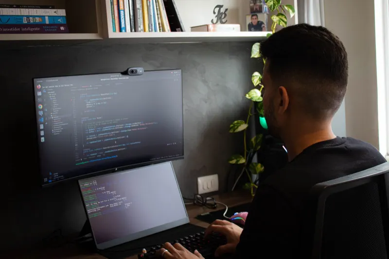 Developer's desk at night with code on monitors and a security warning alert on screen