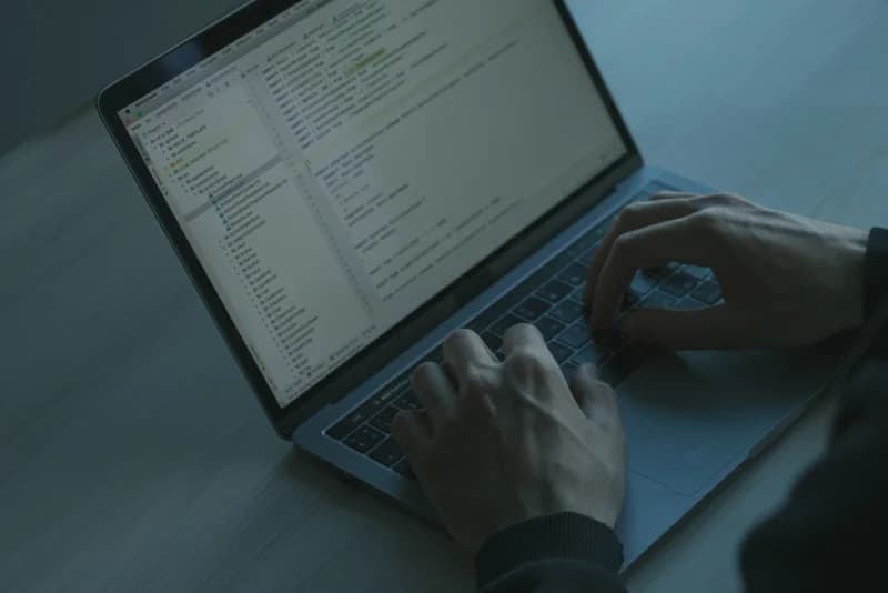 Hands typing on a laptop keyboard with a focus on cybersecurity