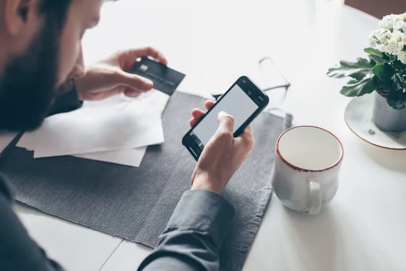 A person making an online payment with a smartphone and credit card