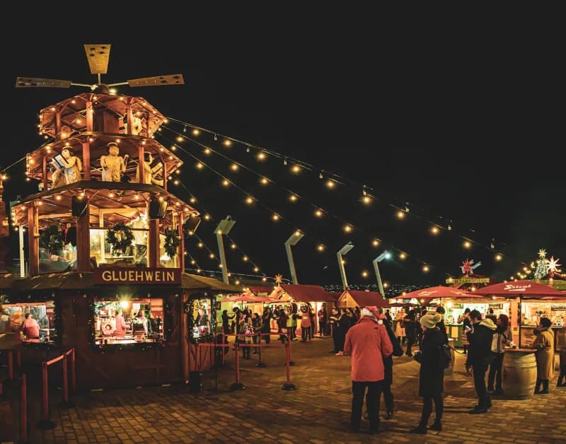 A Christmas market glowing at night with wooden stalls and crowds