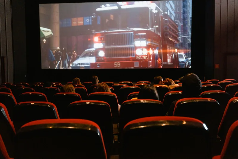 People seated in a cinema watching a movie on a large screen