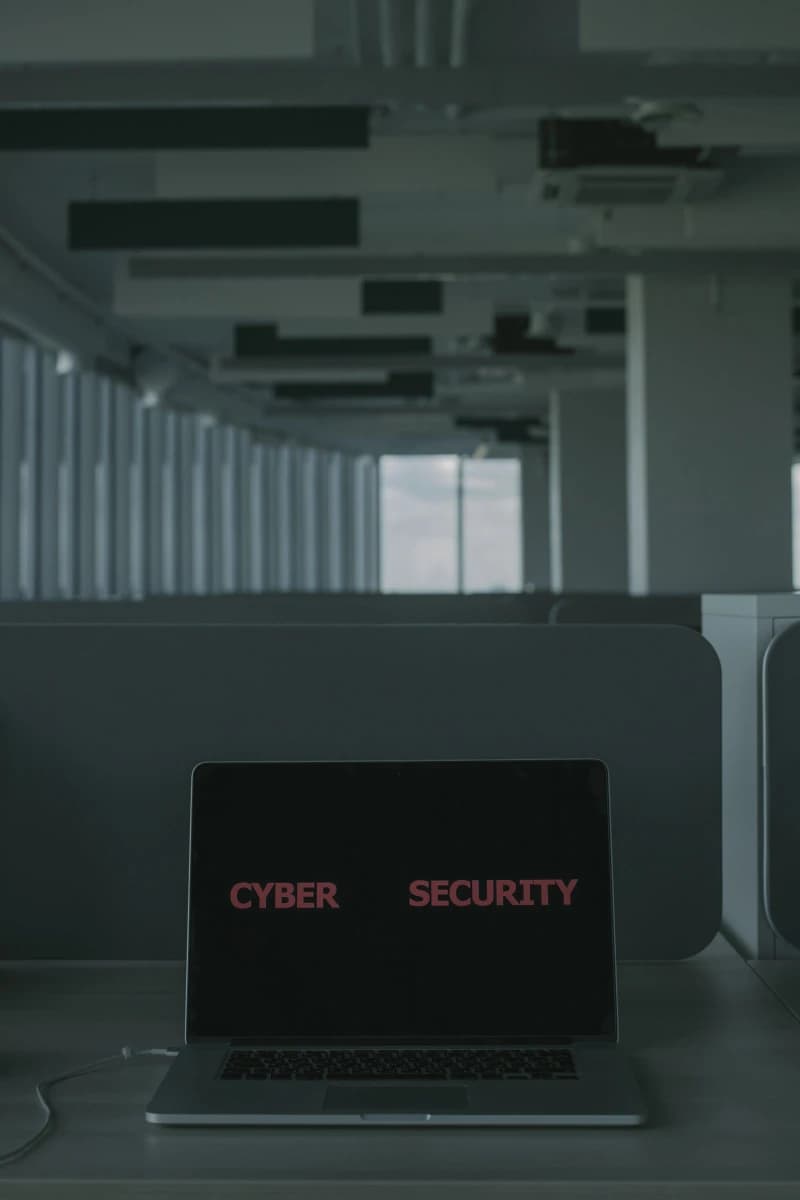 A laptop displaying cybersecurity graphics with a digital padlock overlay on a desk