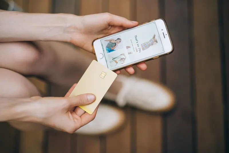 A person holding a smartphone while online shopping, illustrating buy now, pay later debt risks